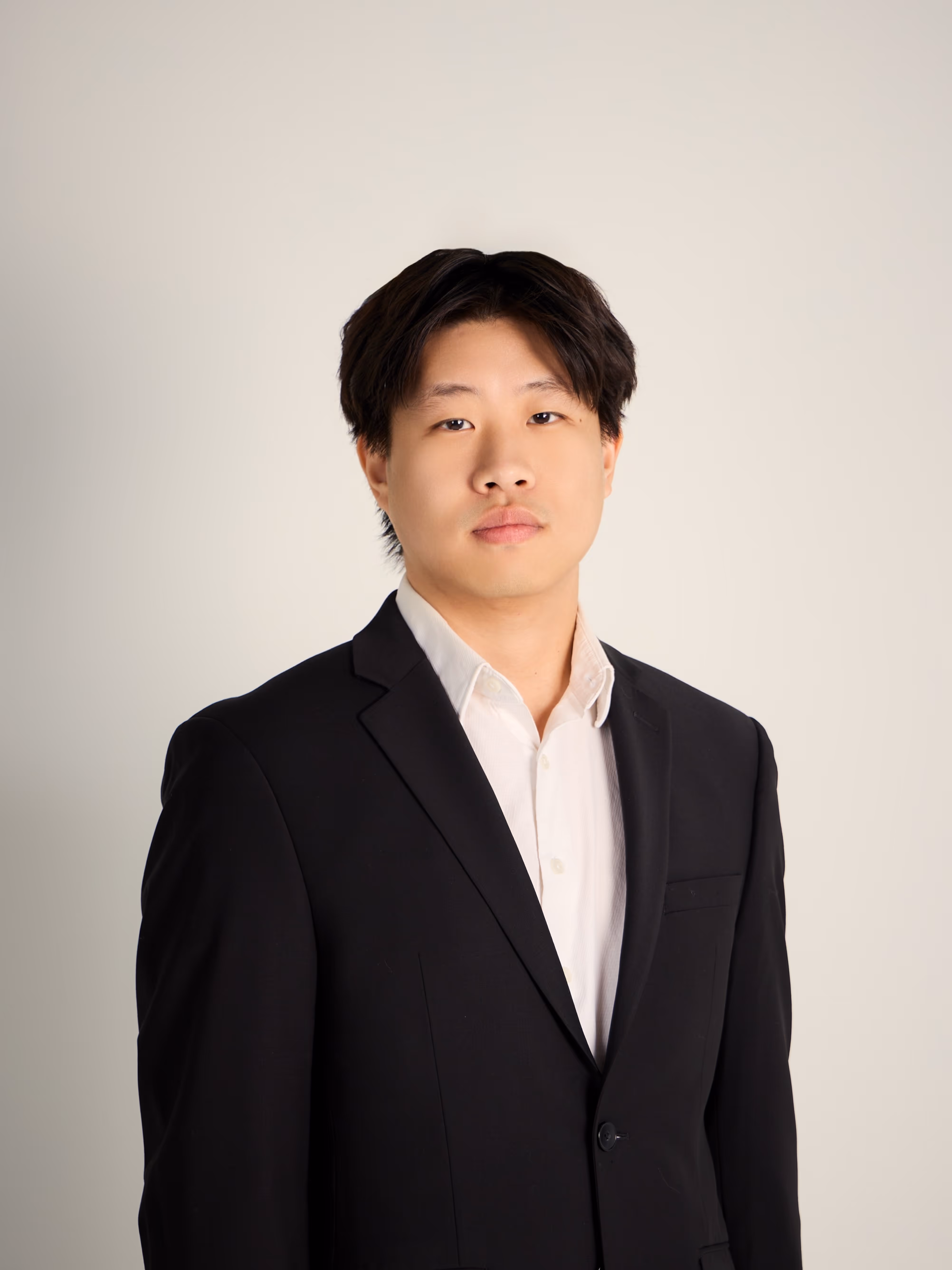 Eric wearing a black suit jacket and white shirt against a plain light background.