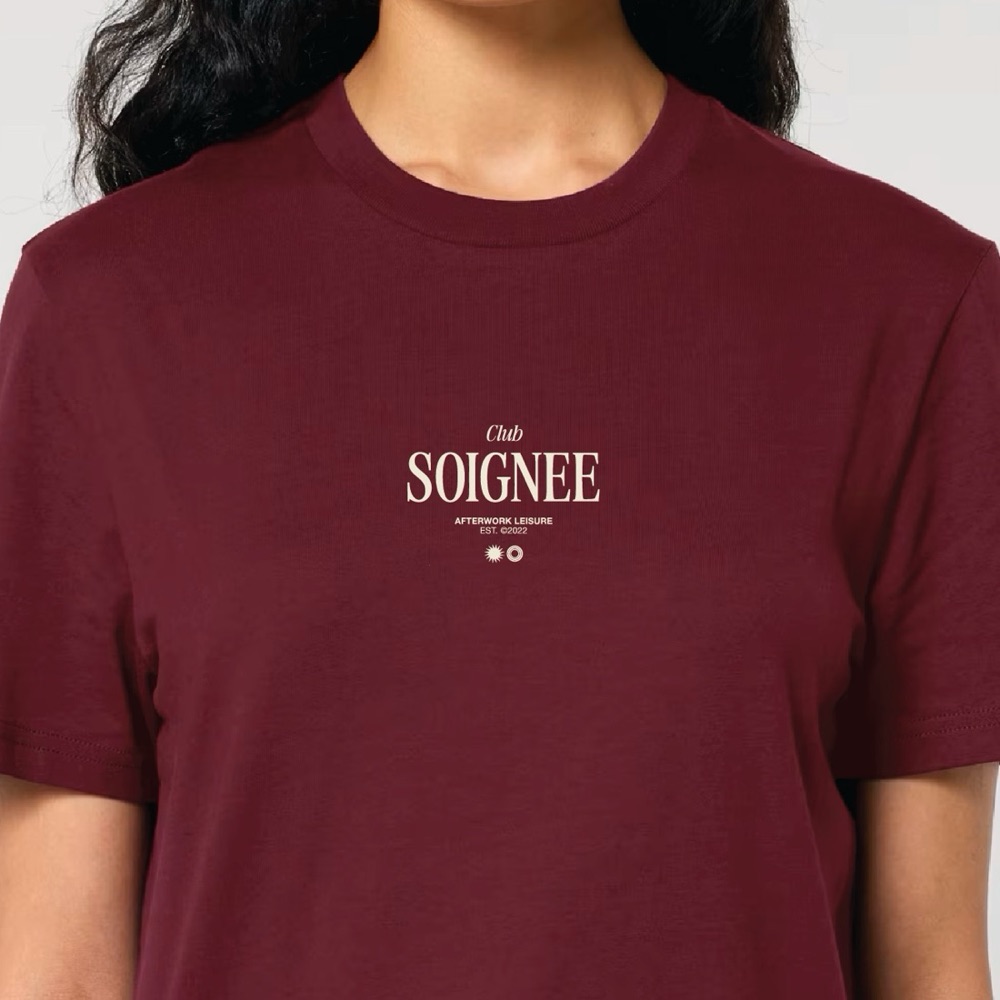 Close-up van het Club Soignee-logo op de borst van het Burgundy shirt