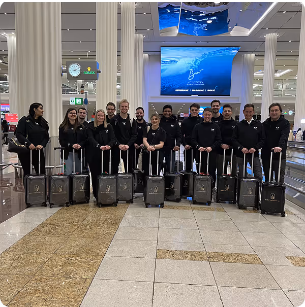Groep mensen in uniformen met rolkoffers op een luchthaven.
