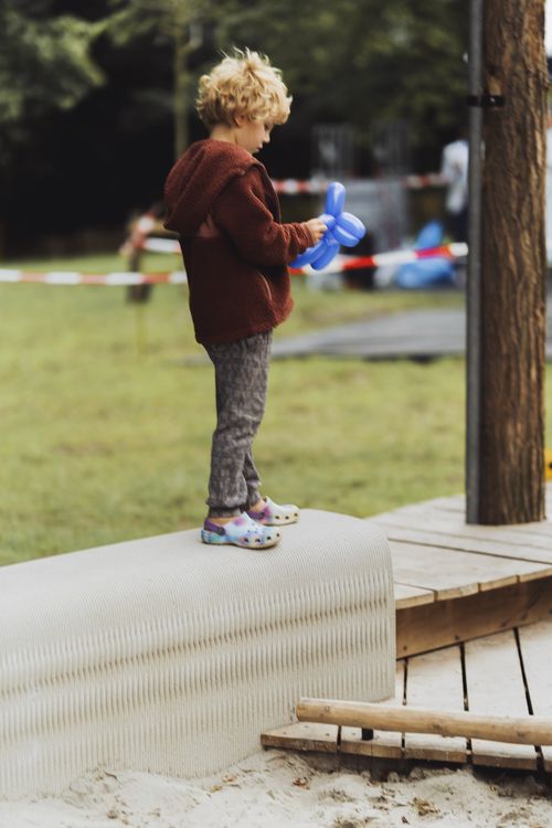 A young boy exploring the 3D-printed sandbox bench, emphasizing its role as an interactive and eco-friendly playground feature