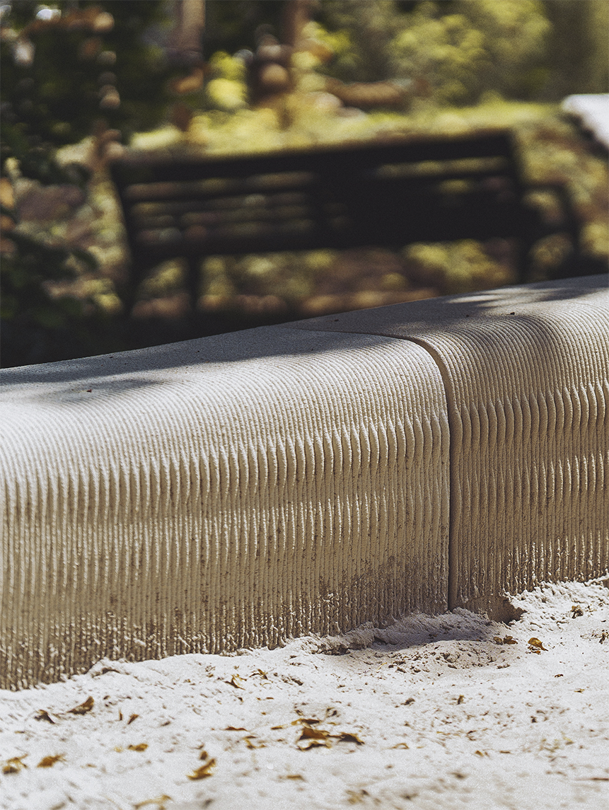 Close-up of the textured surface of the 3D-printed sandbox bench, highlighting its sustainable concrete material and layered design