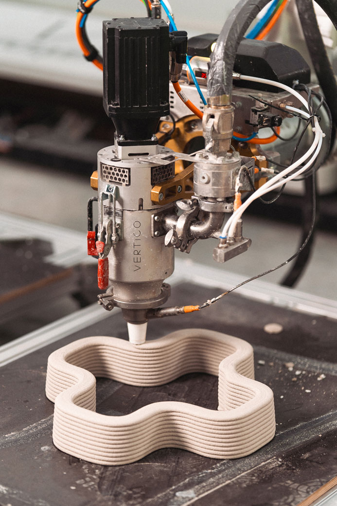 Close-up of a Vertico robotic 3D printer nozzle extruding concrete in a precise, complex pattern for stay-in-place formwork.