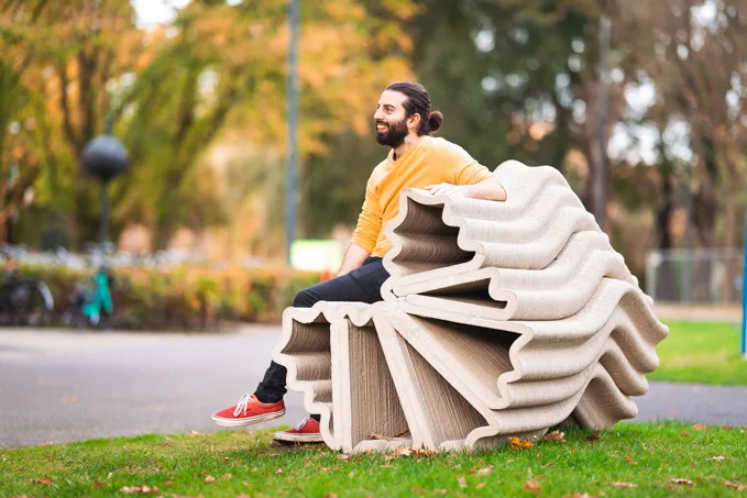 3D-printed concrete bench with wavy design in autumn park setting