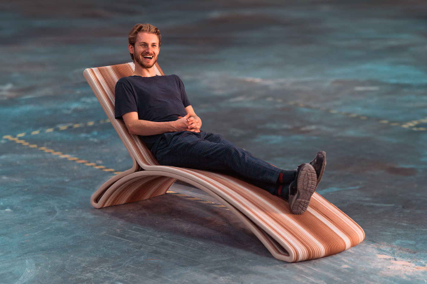 3D printed concrete lounge chair with curved wooden design, person seated