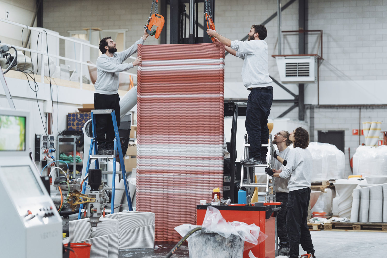 3D concrete printing workers manipulate large reddish-brown printed structure
