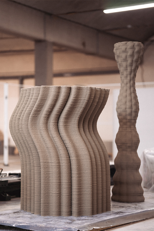 Curved 3D printed concrete sculptures with layered, wavy texture