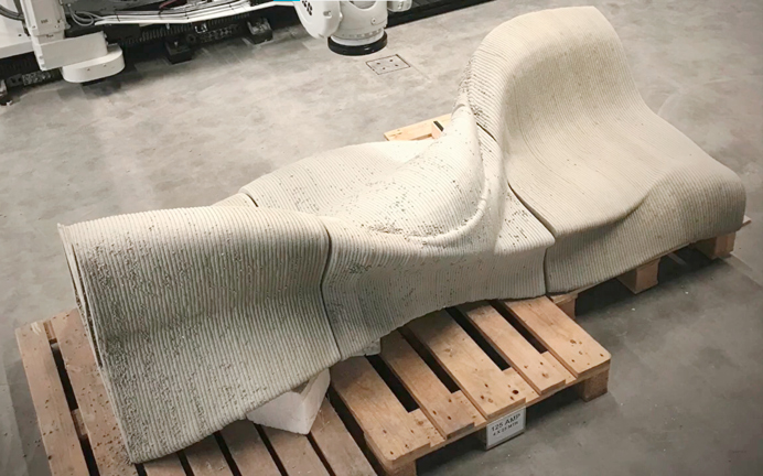 Large curved white 3D-printed seat or furniture piece on wooden pallets