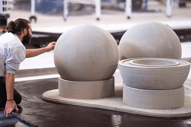 3D printed spherical objects being crafted by a worker in an industrial setting