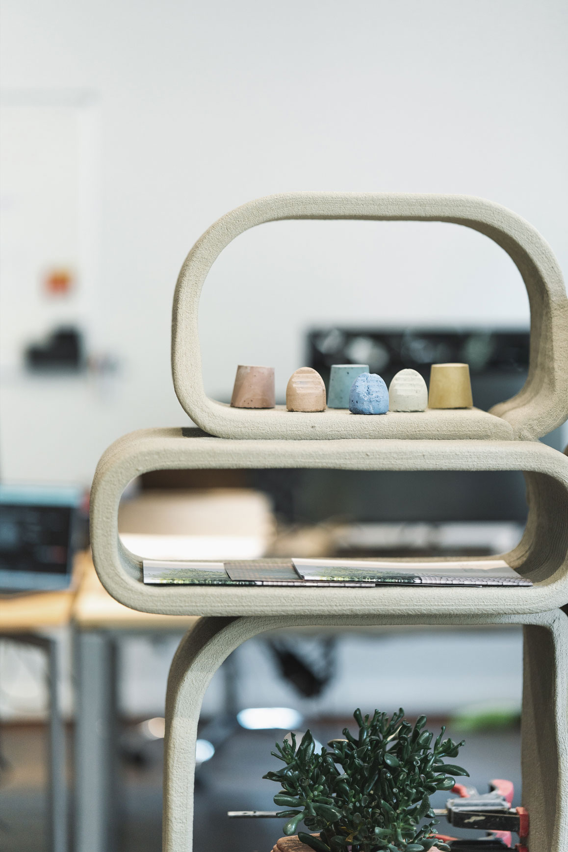 Curved concrete shelving with minimalist design and colorful ceramic objects