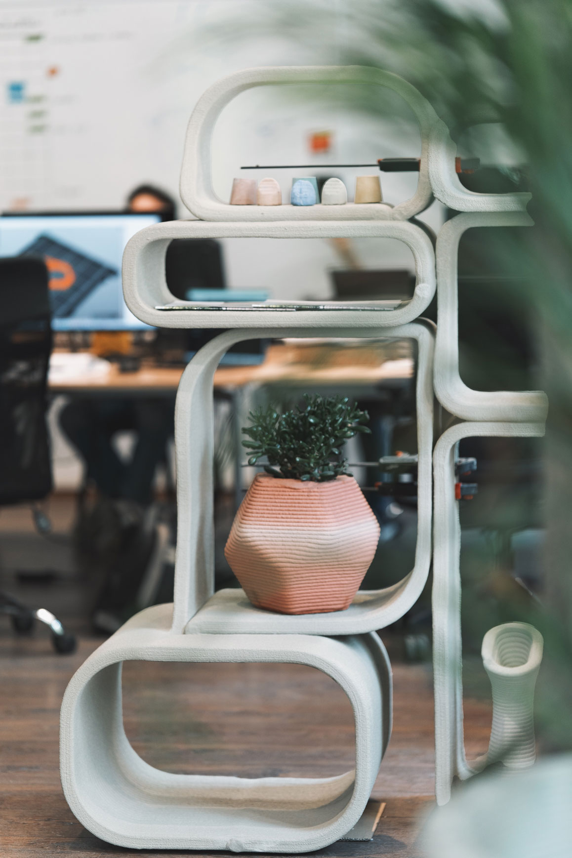 Curved concrete design shelving unit with potted plant and decorative objects