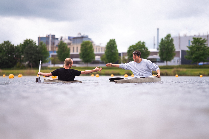 Two kayakers interact on concrete urban waterway with modern design background