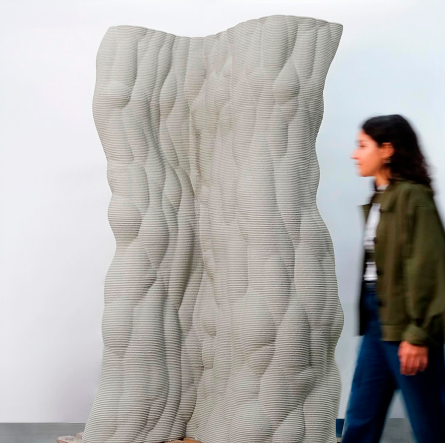 Textured concrete sculpture with organic design, large vertical form next to person