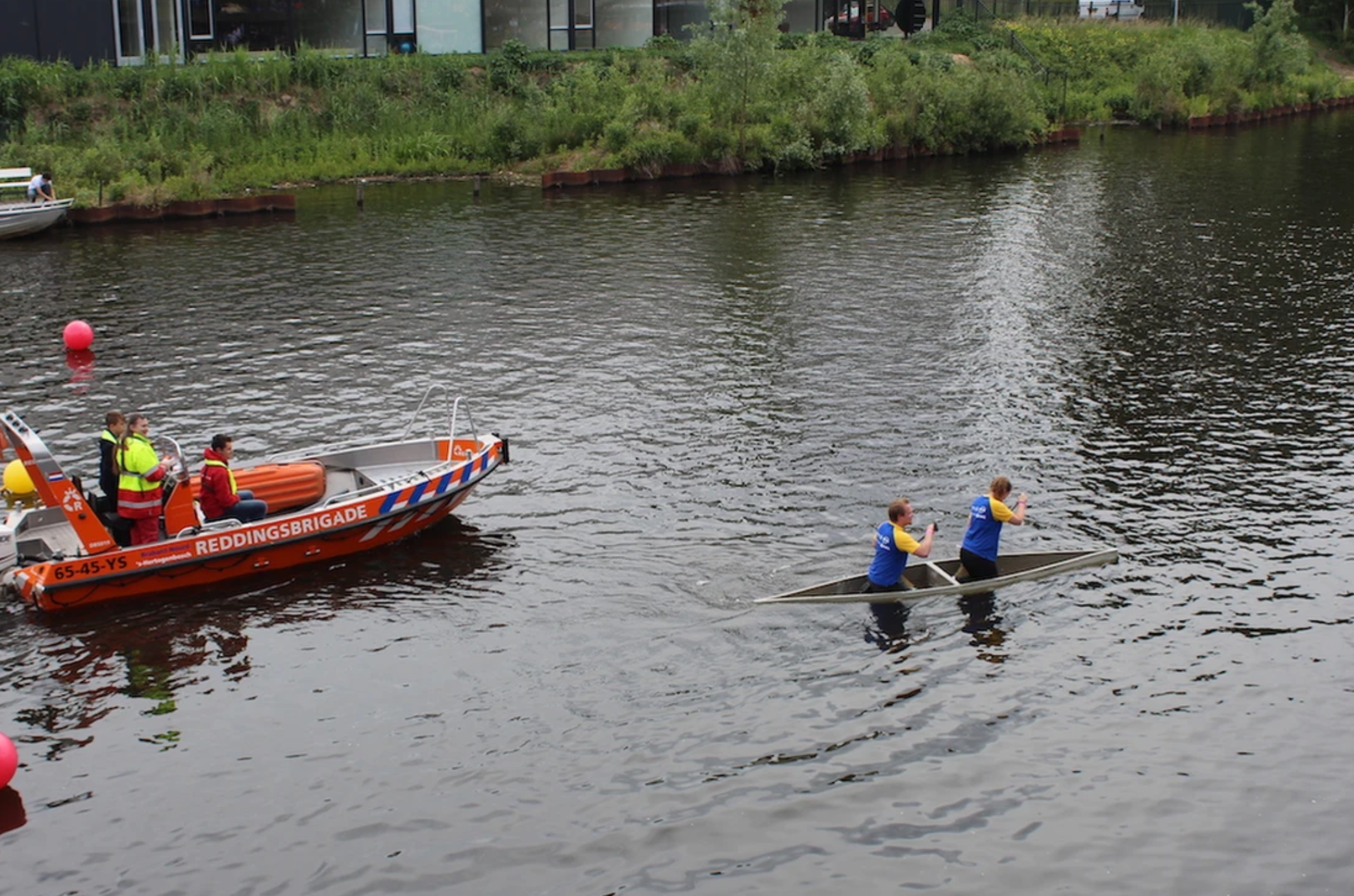 Rescue boat near concrete canal with kayakers during community printing projects