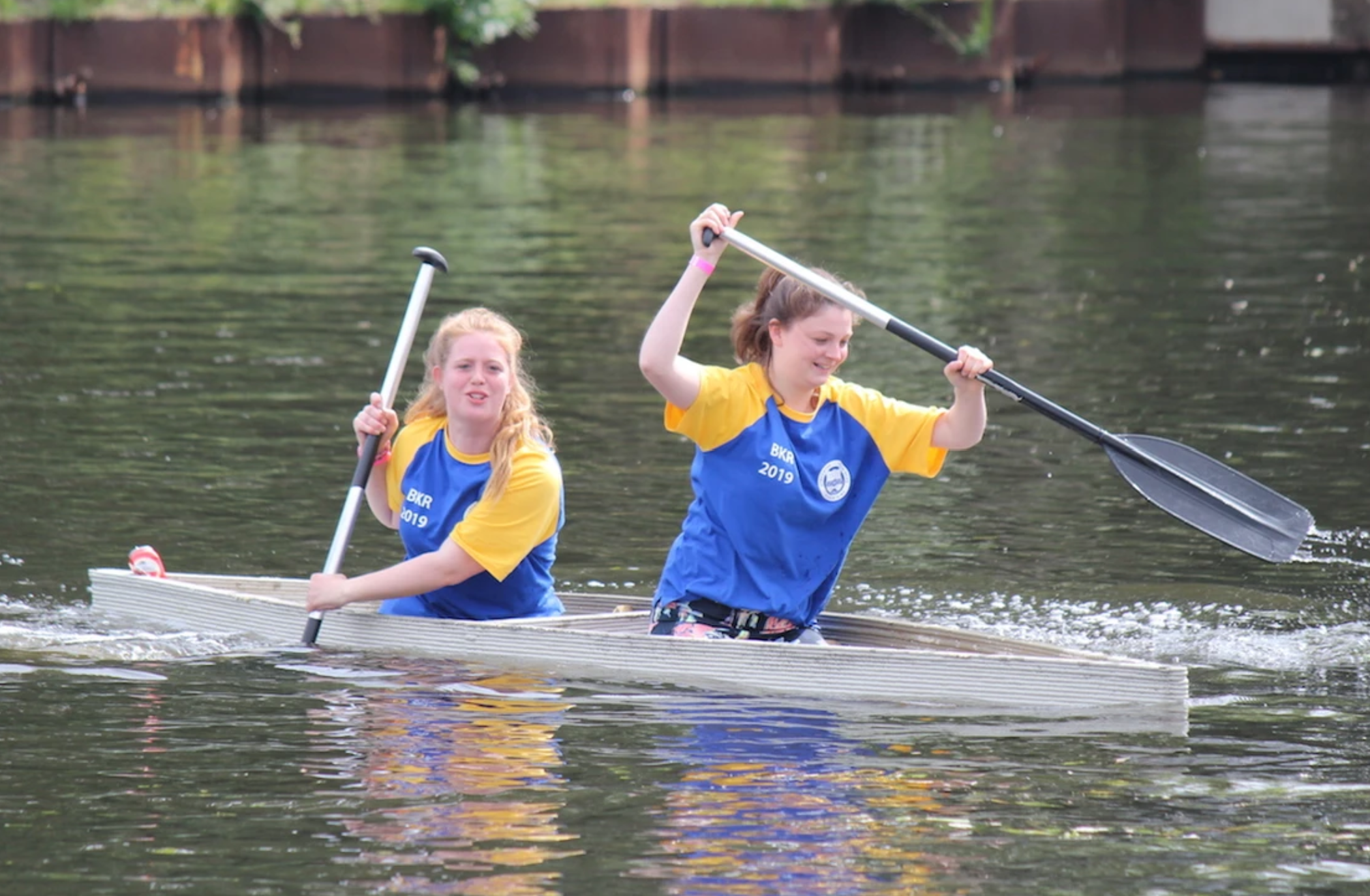 Concrete kayaking projects team paddling in yellow-blue uniforms on water