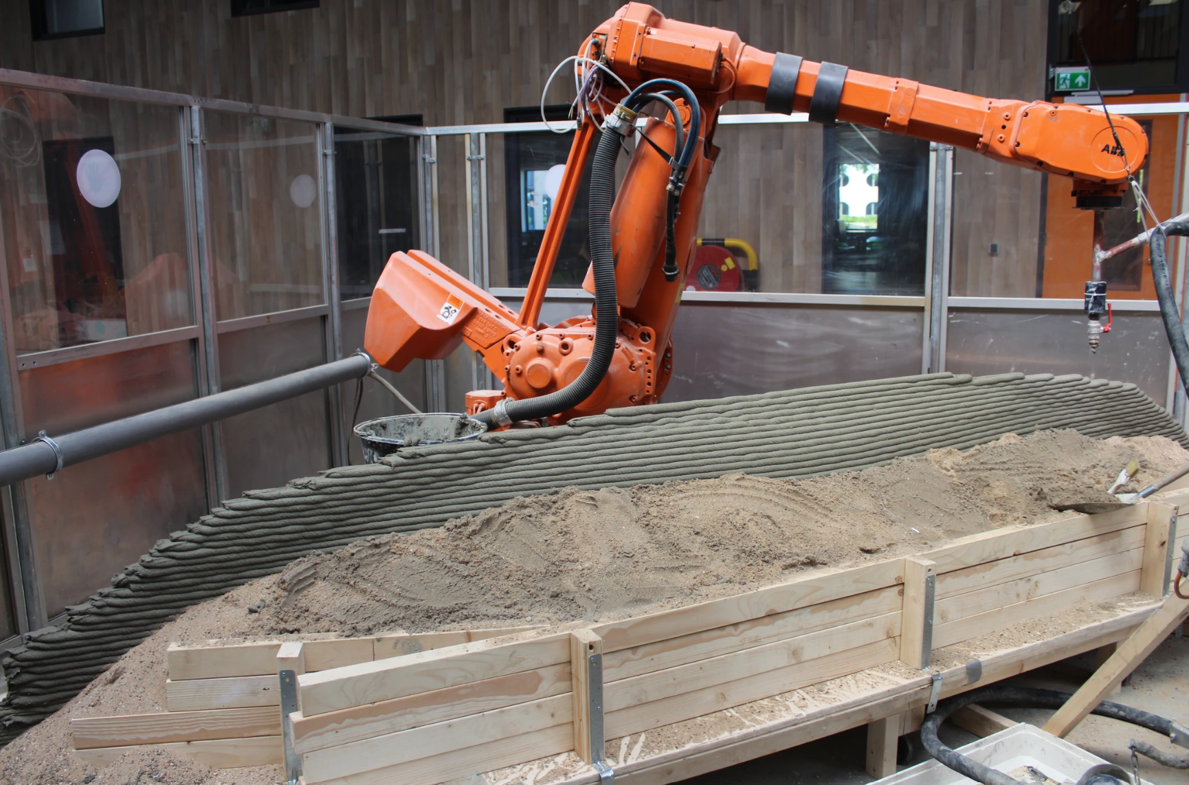 Orange robotic arm 3D printing concrete for innovative construction projects