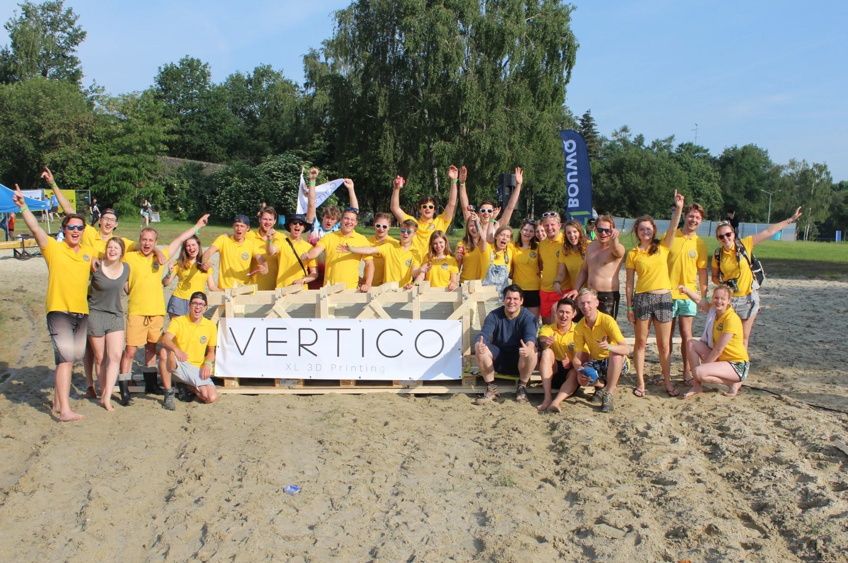 Team in yellow celebrates concrete printing projects with Vertico banner