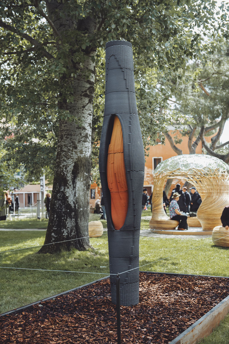 Modern sculptural column with orange interior in park setting