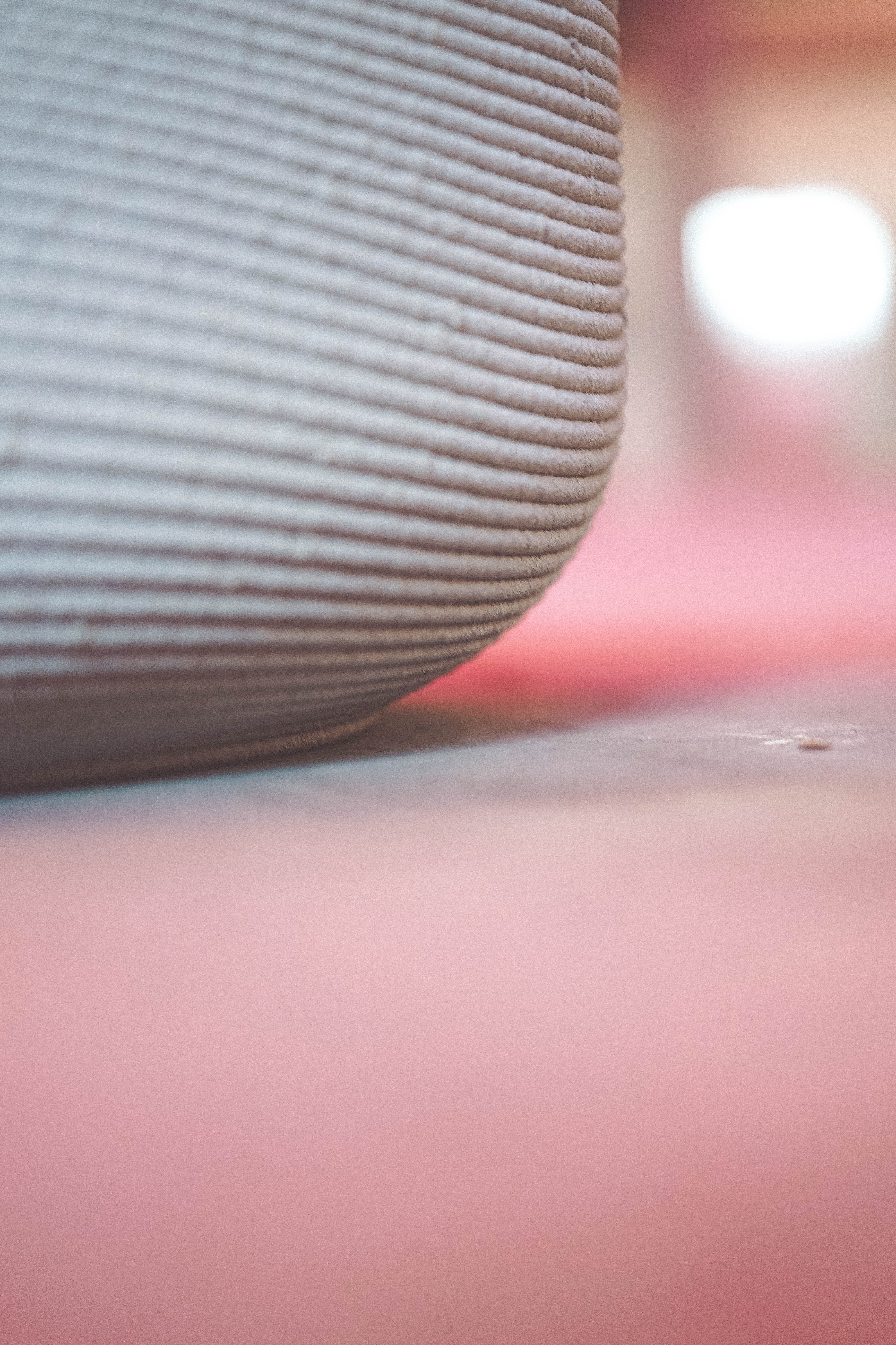 Close-up of ribbed ceramic vase on soft pink background with blurred light