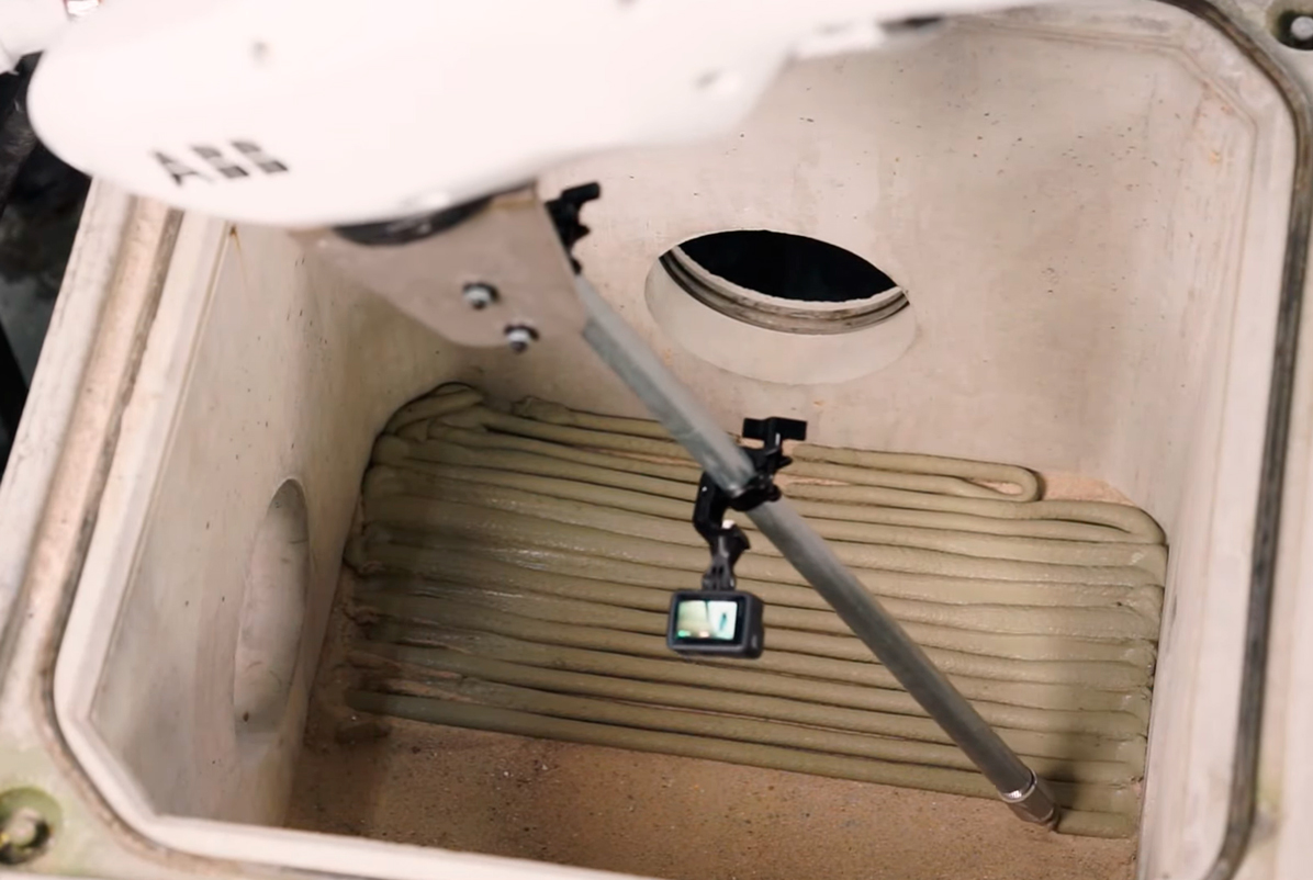 Small camera mounted on metal arm inside white equipment compartment