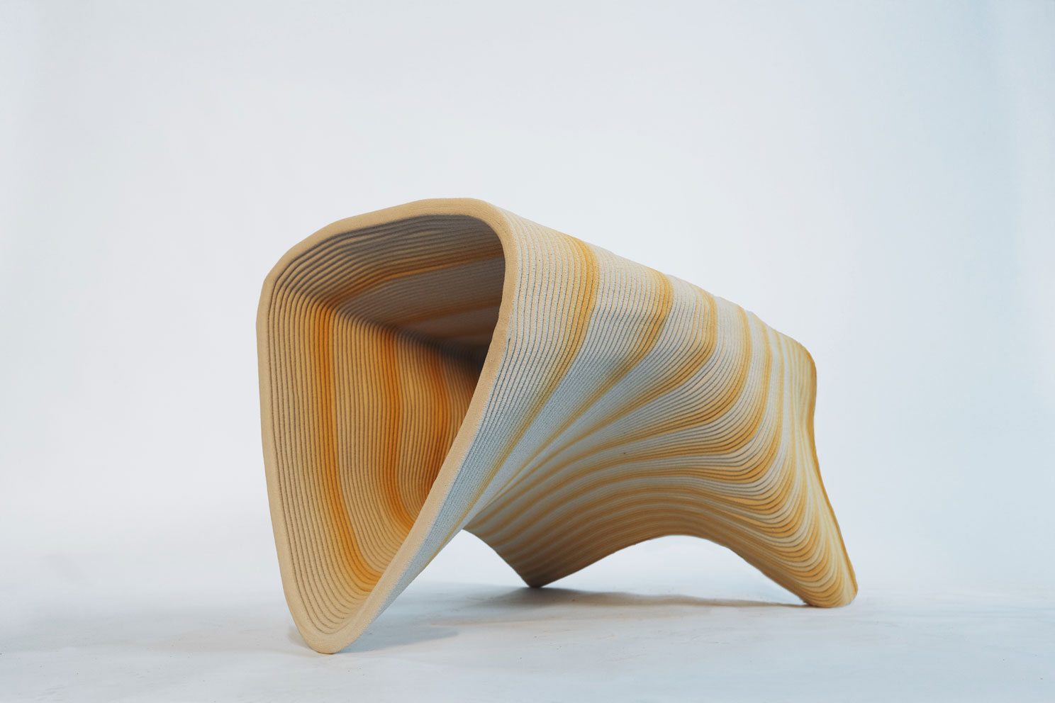 Curved wooden sculpture with layered yellow and white undulating lines