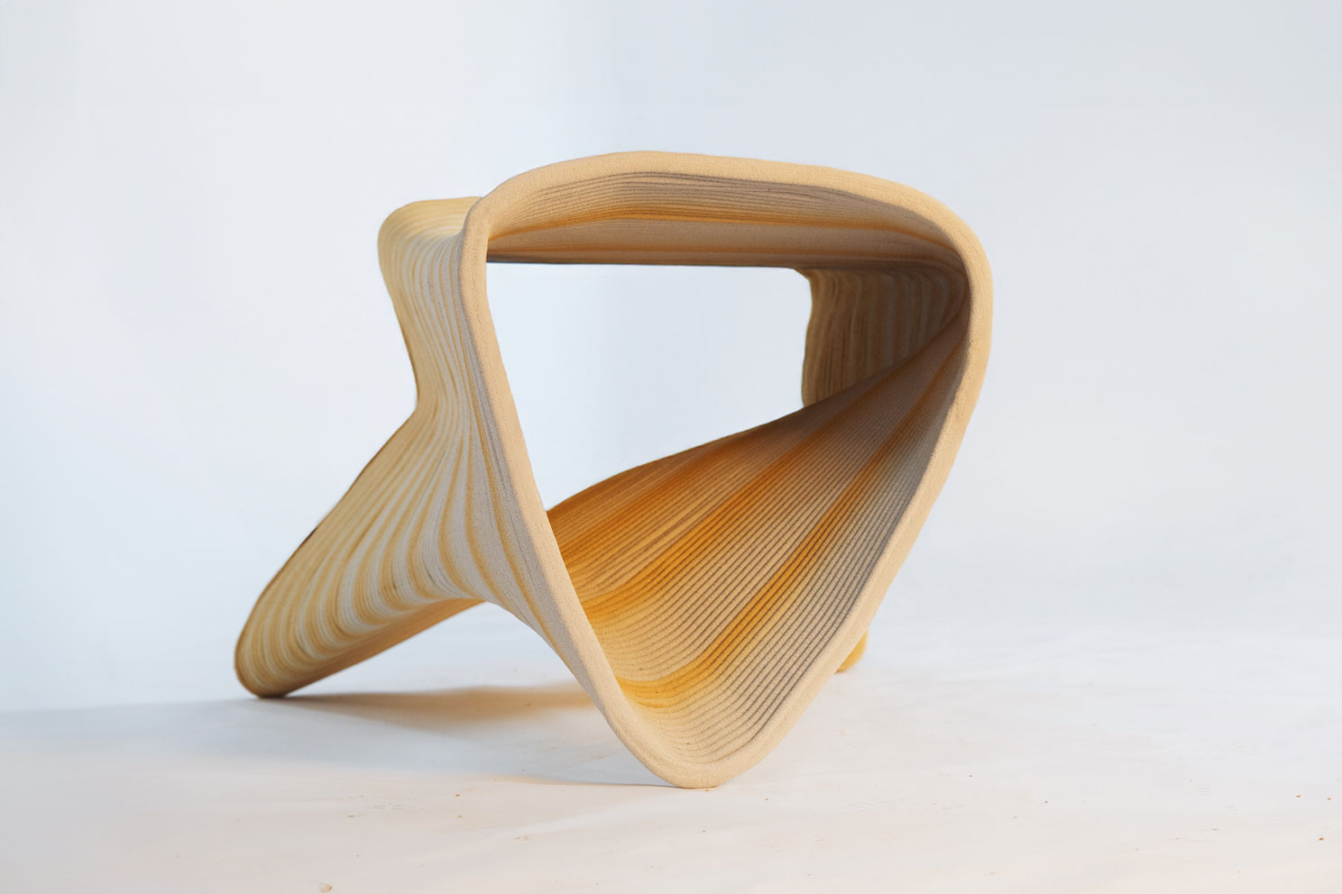 Curved wooden sculpture with smooth, layered texture against white background