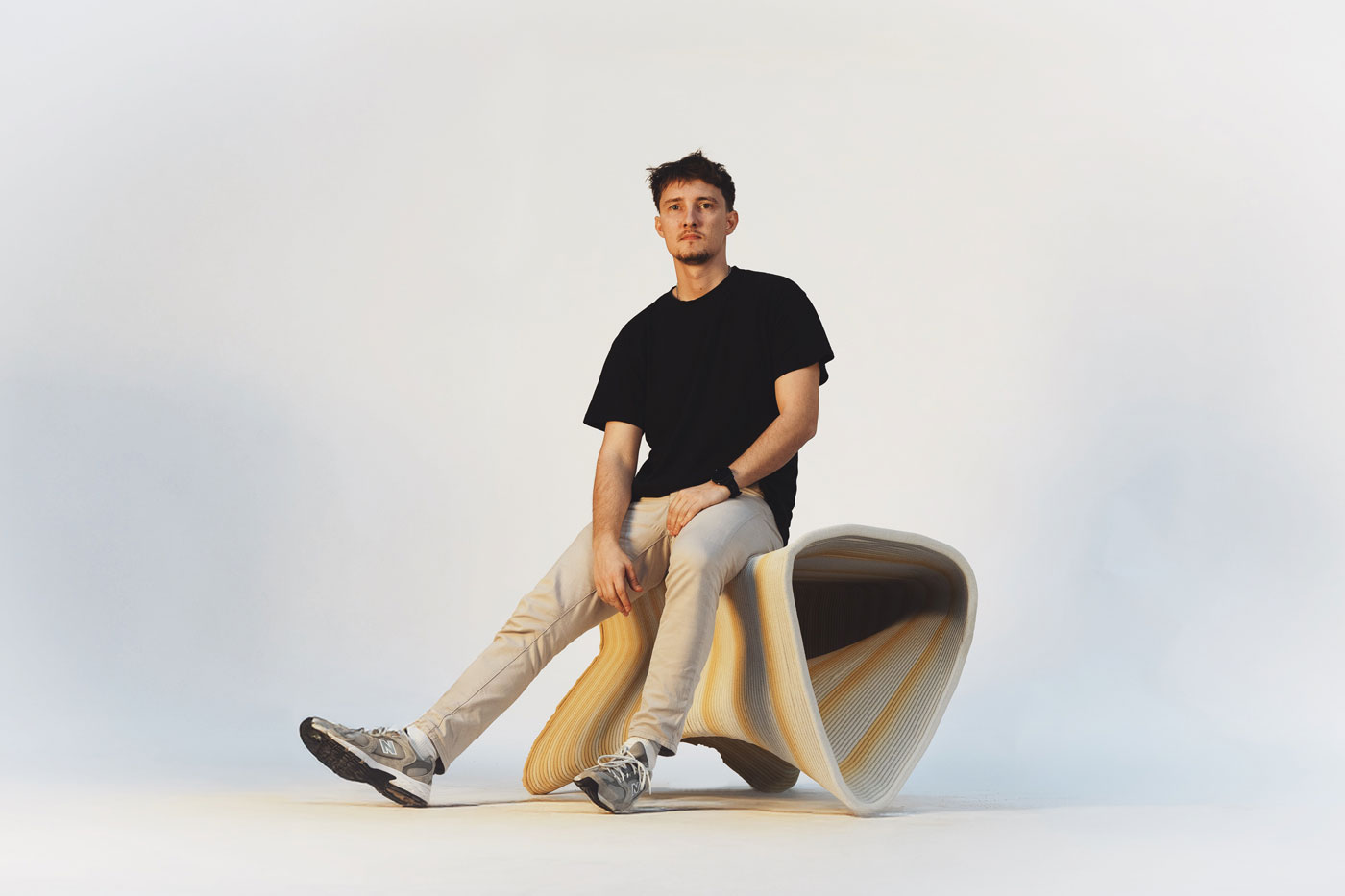 Person in black shirt sitting on curved yellow and white design seat
