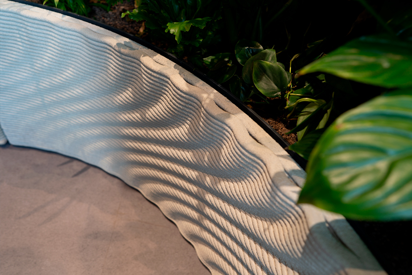 3D printed concrete bench with wavy topographical texture in garden