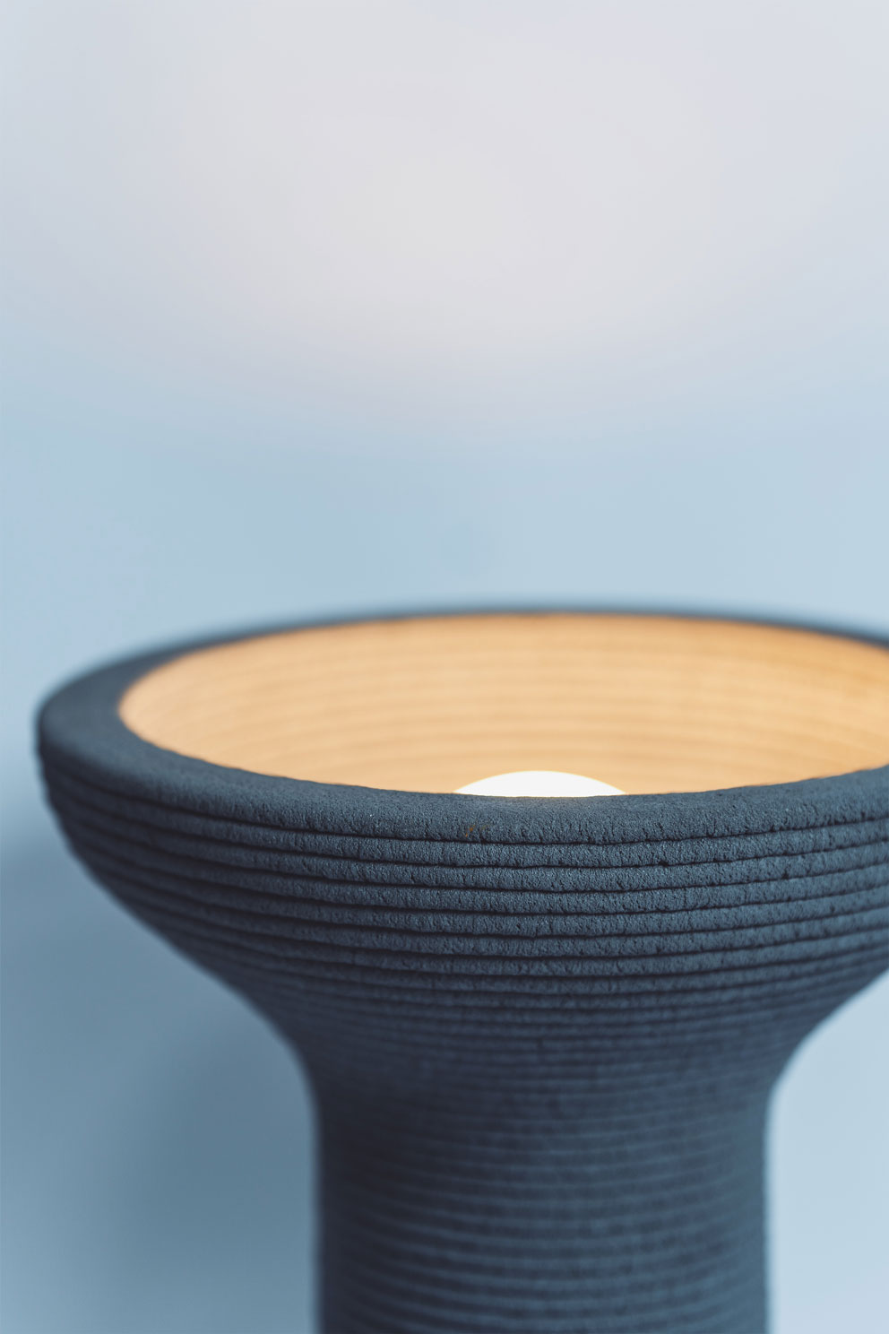 Textured blue ceramic vessel with wooden top against soft blue background