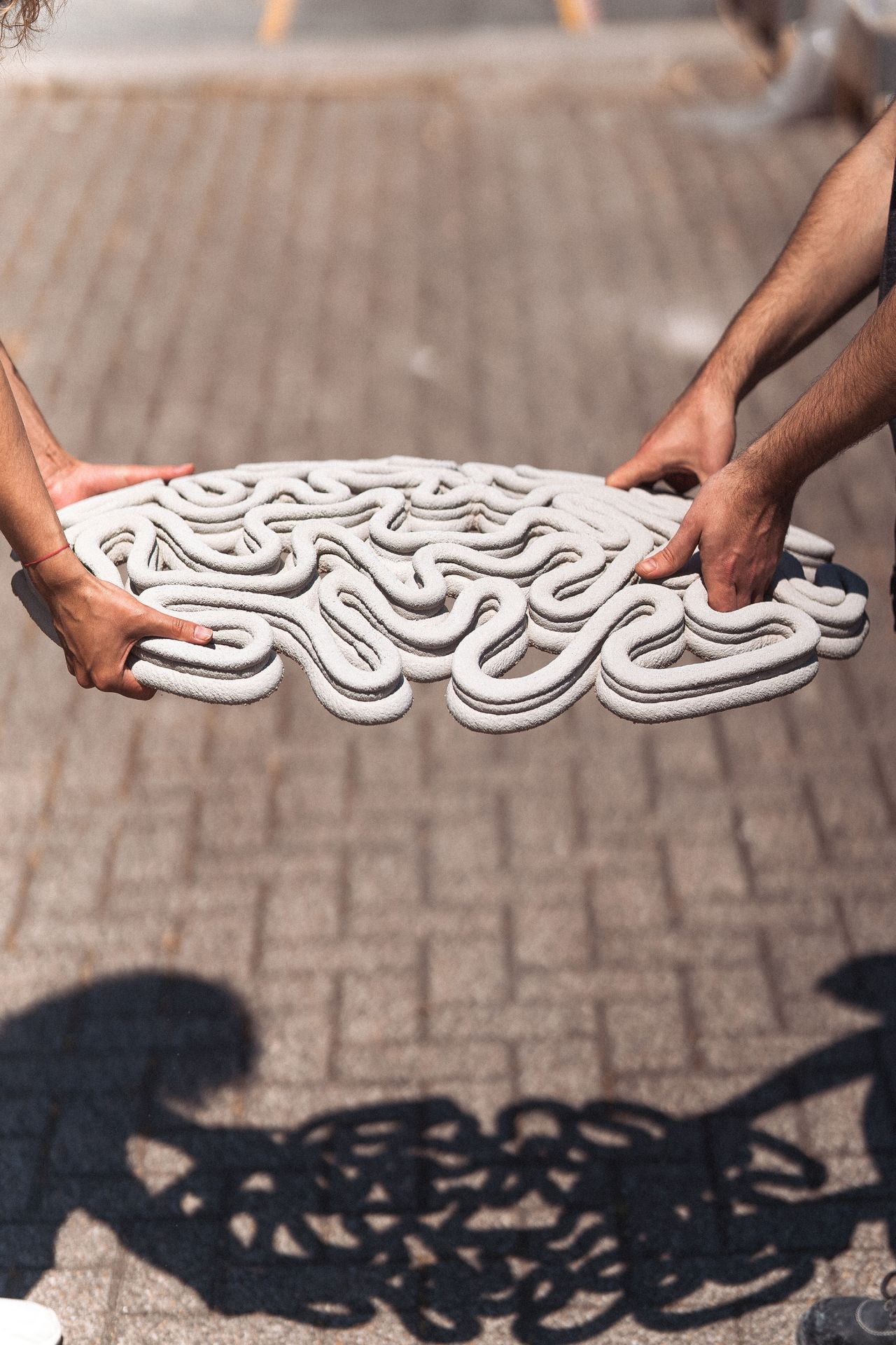 3D concrete printing project with intricate curved design held by hands