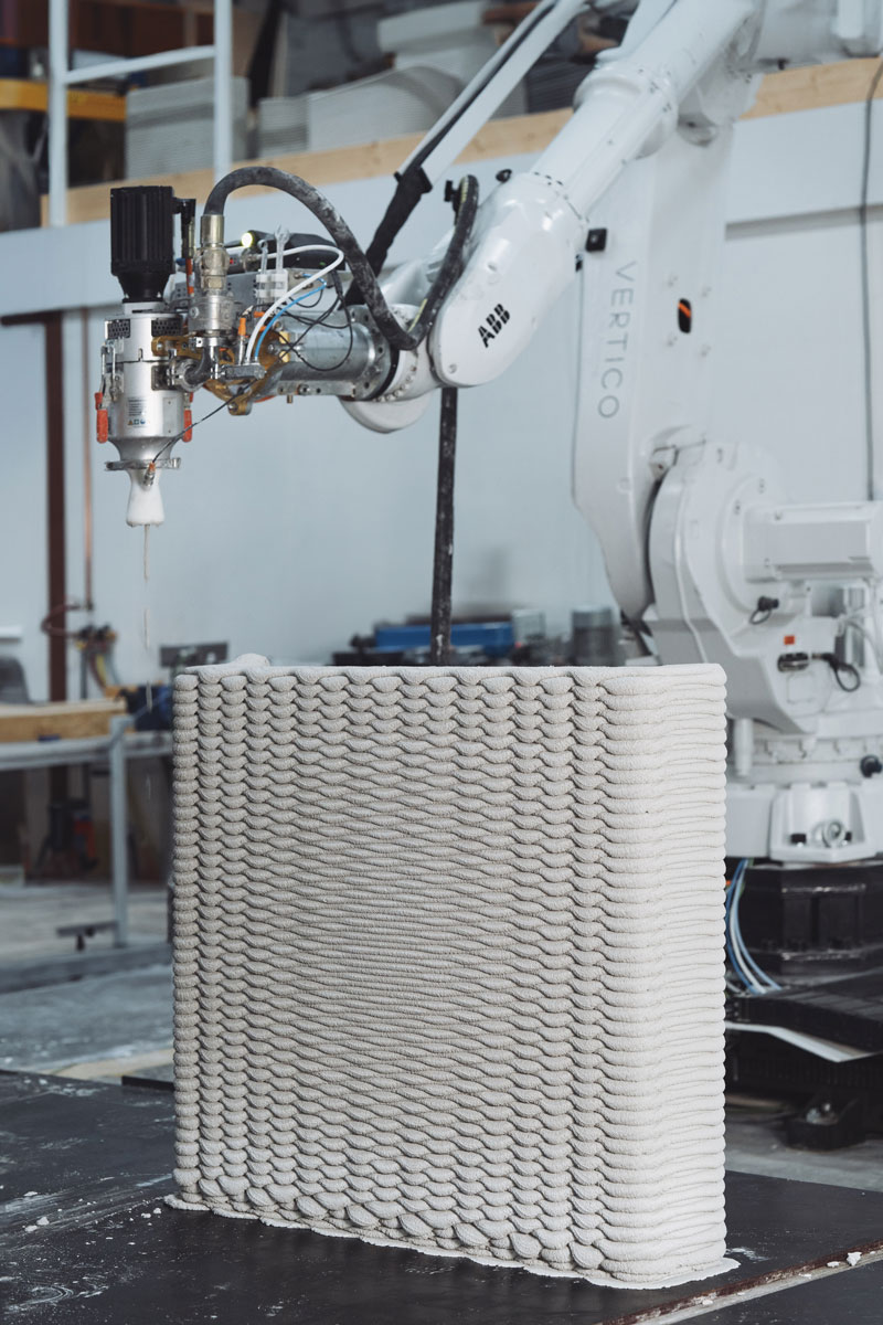 3D concrete printing robot creating textured wall structure in workshop