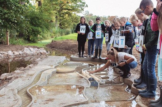 Students explore water flow in outdoor sand and water landscape model