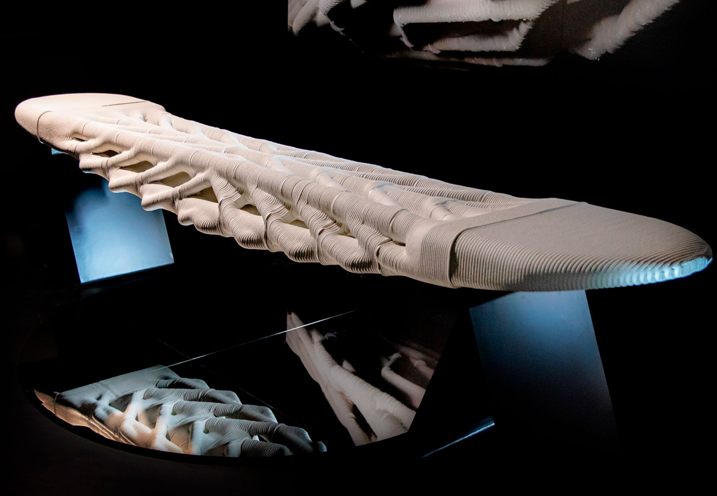 Sculptural white model with contoured layers on blue-black display