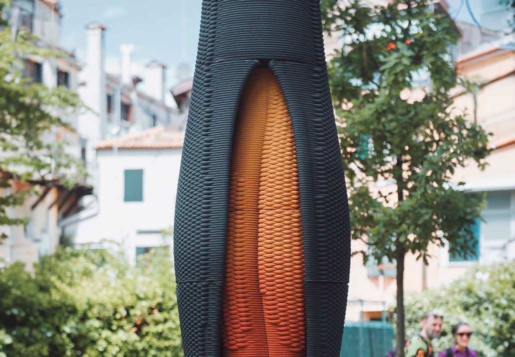 Textured black and orange column with curved shape in urban setting