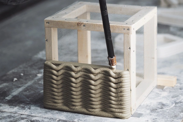 3D printed clay structure with wavy texture inside wooden mesh frame