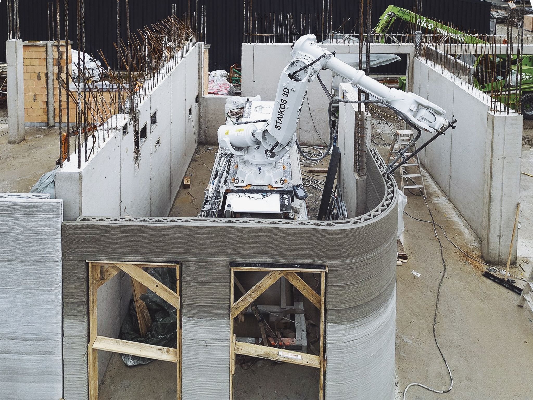 3D concrete printing robot constructing curved wall at construction site