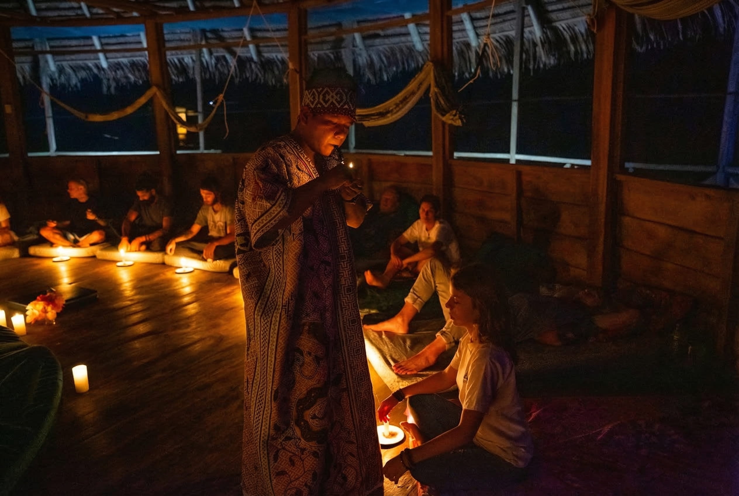 A dark Peruvian ceremony lit by candles with a Shipibo shaman. 