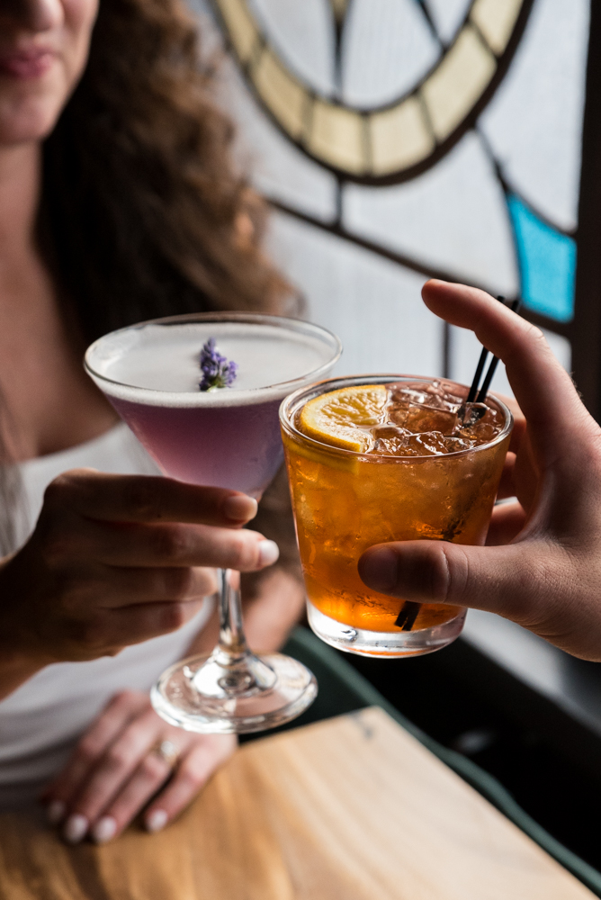 Two guests toasting with craft cocktails at The Caz