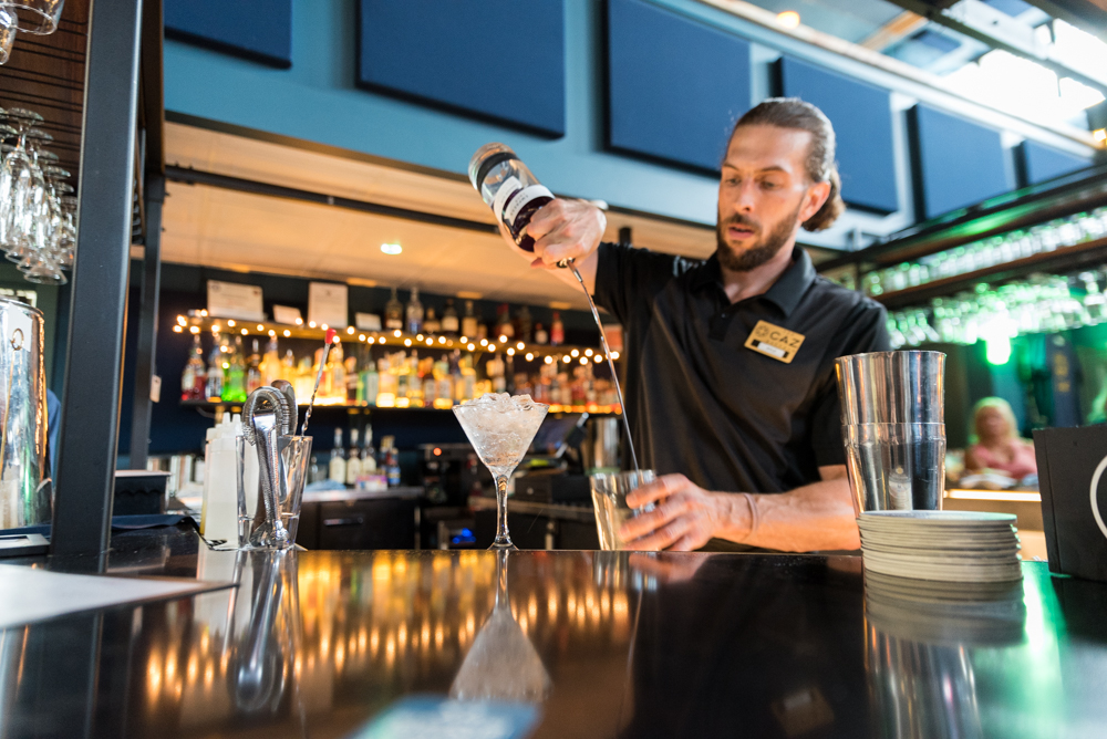 A bartender pouring a cocktail at The Caz bar