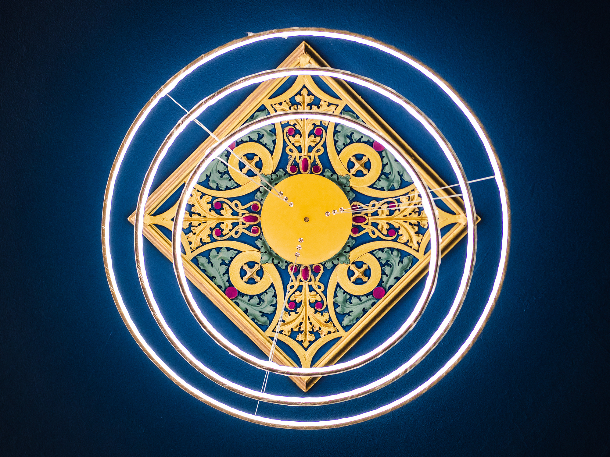 Gold and blue ceiling medallion framed by circular lights at The Caz