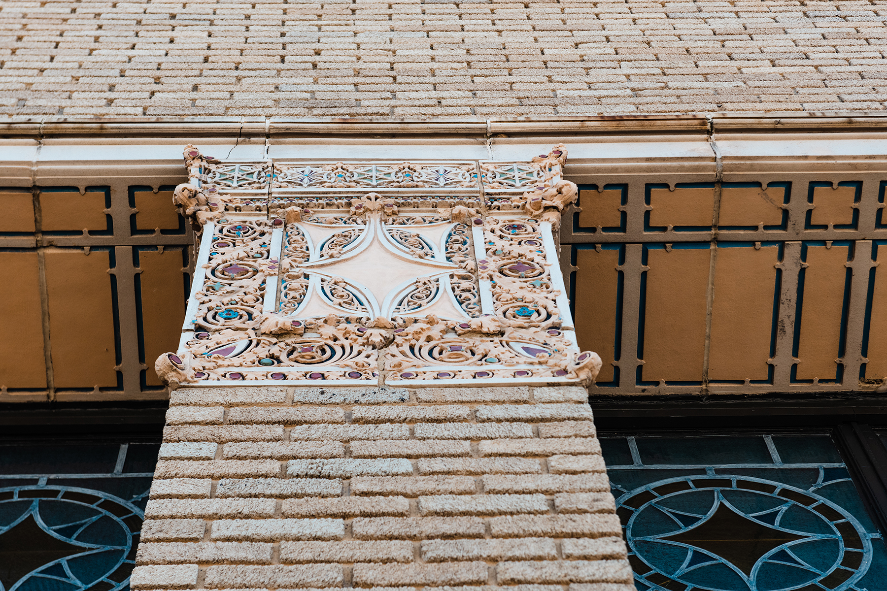 Ornate terra cotta capital atop a brick pillar on the exterior of The Caz