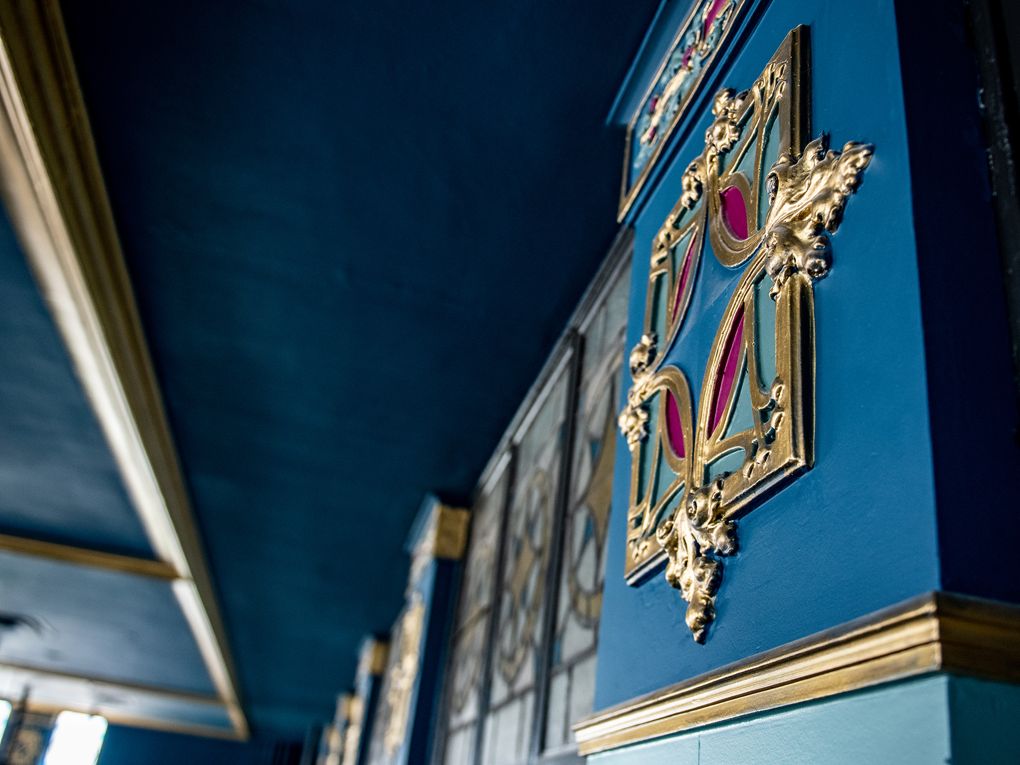 Ornate gold and blue decorative panels along the ceiling at The Caz