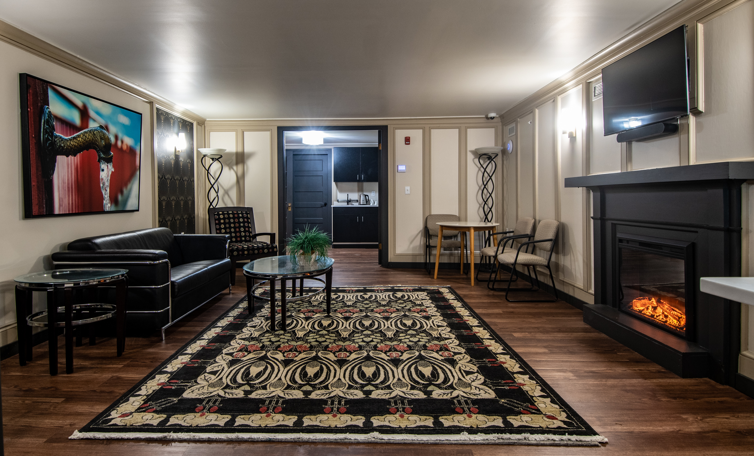 The Caz green room with a sofa, fireplace, and patterned rug