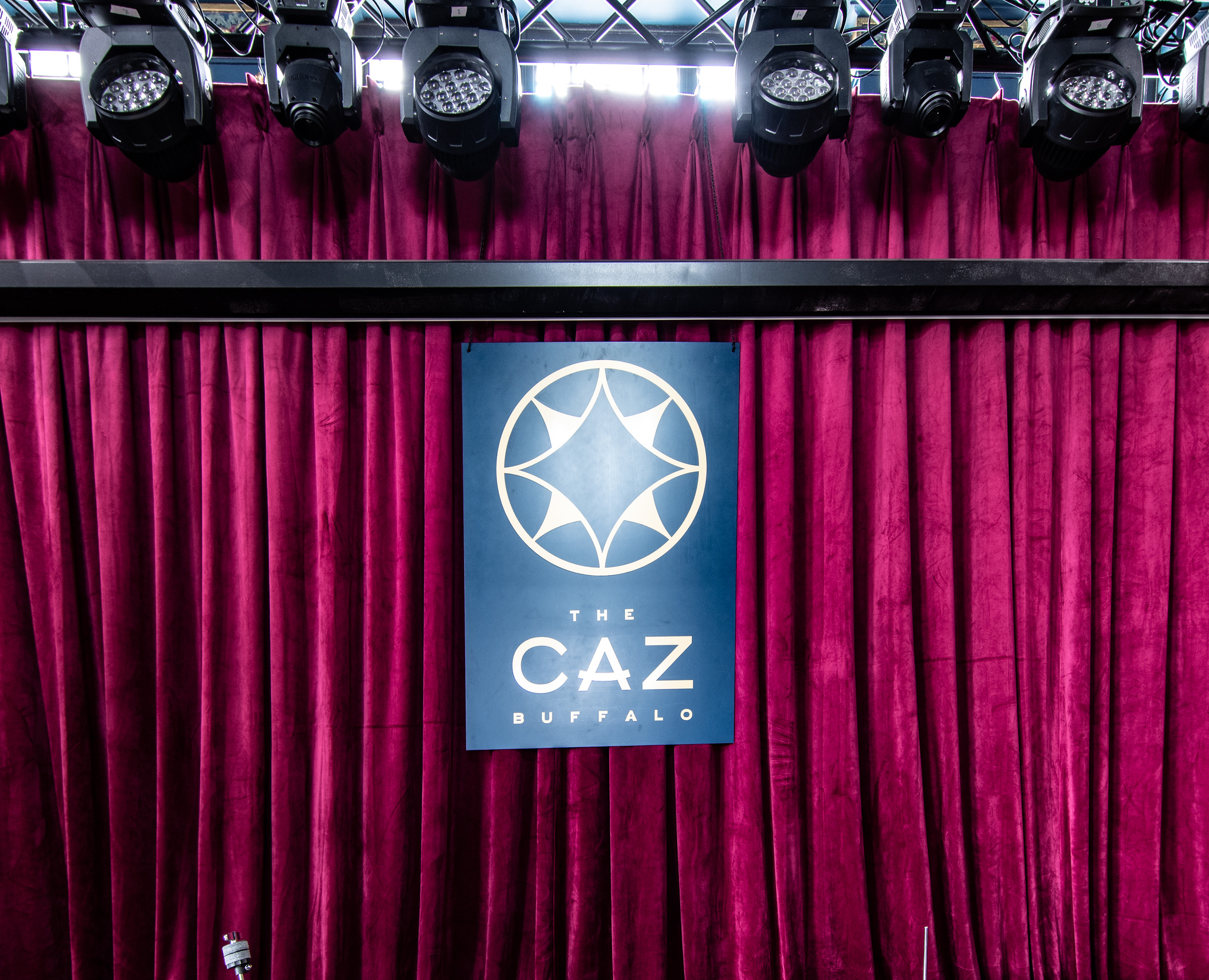 The Caz stage with red velvet curtains and the Caz logo banner