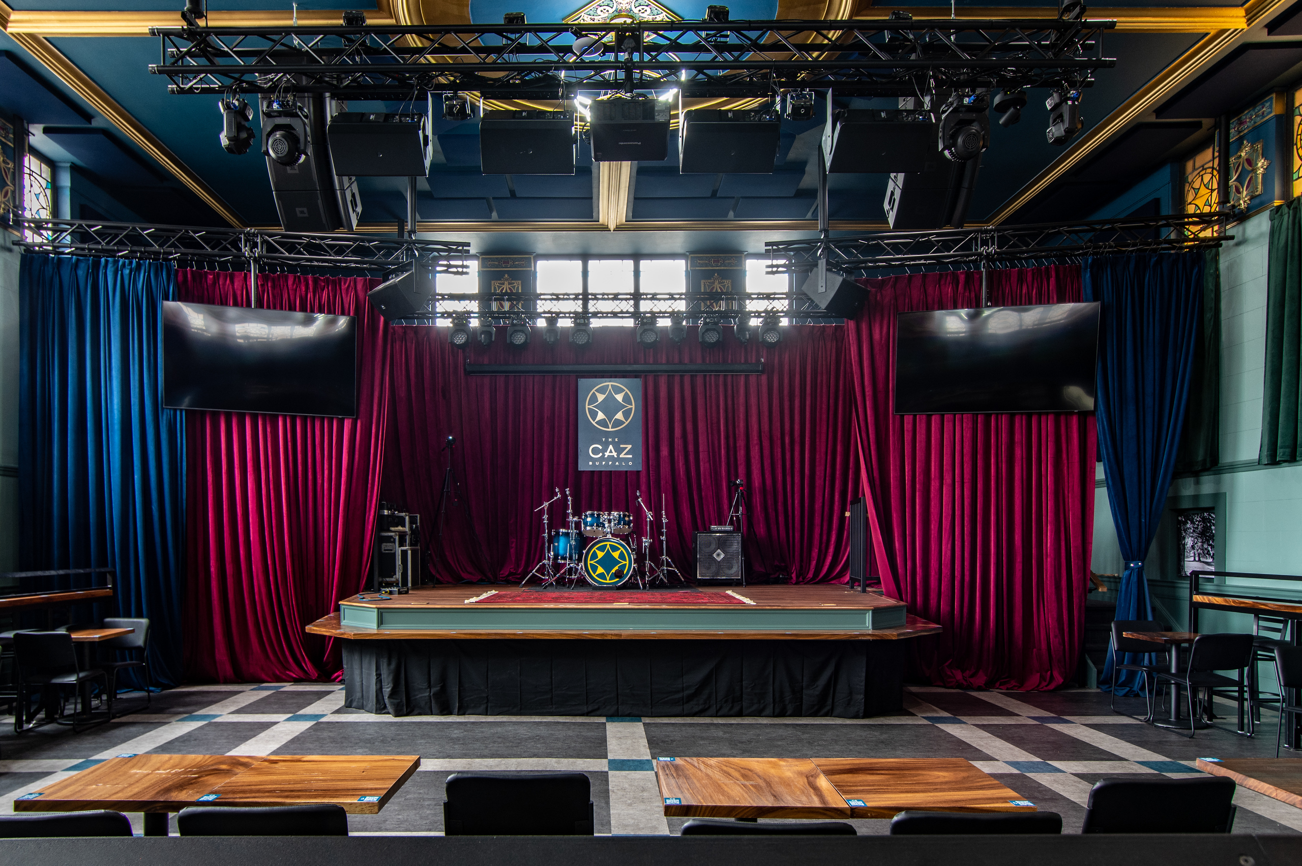The Caz stage set up with drums in front of red velvet curtains