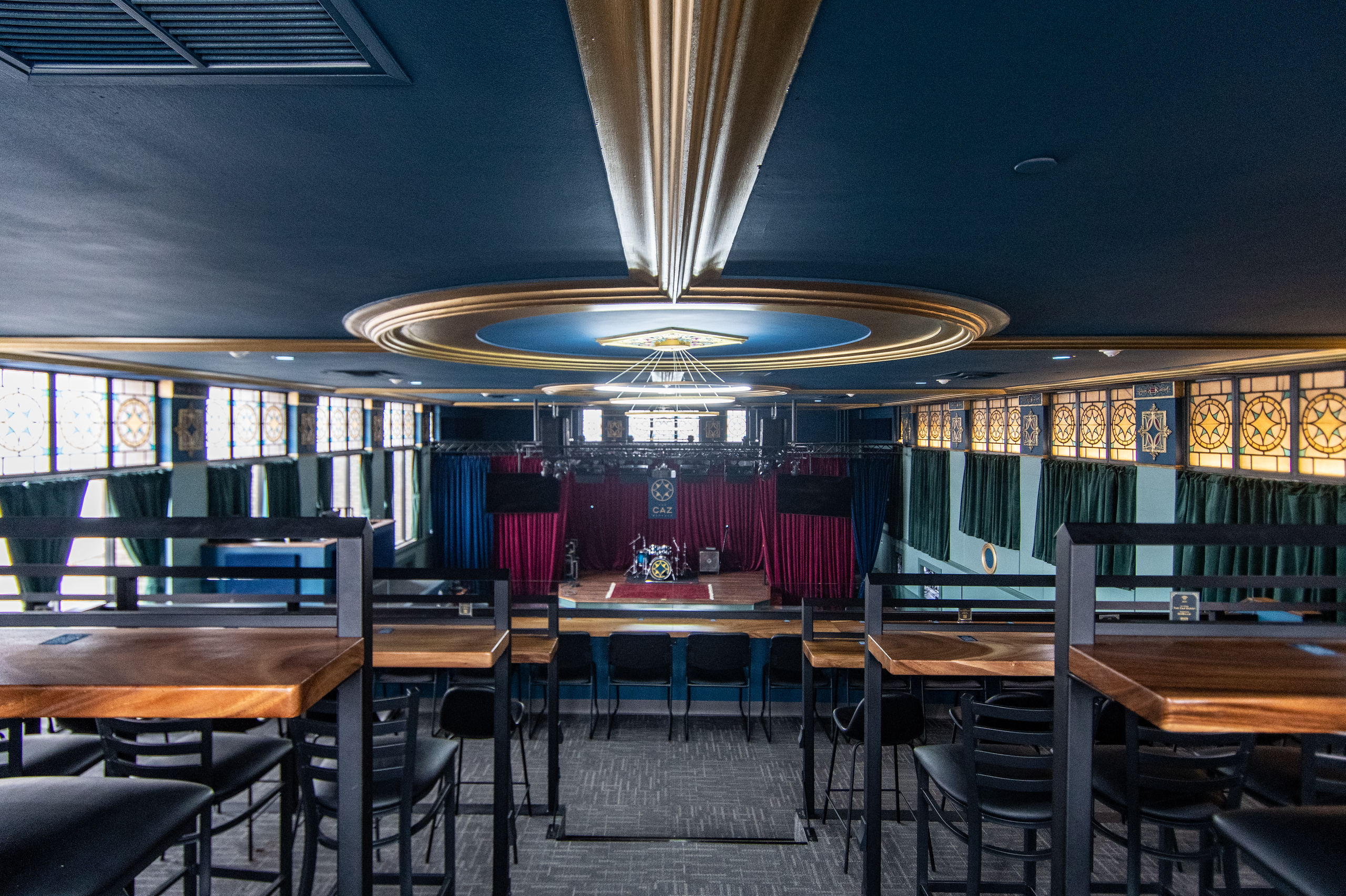 Mezzanine tables beneath a gold ceiling medallion at The Caz