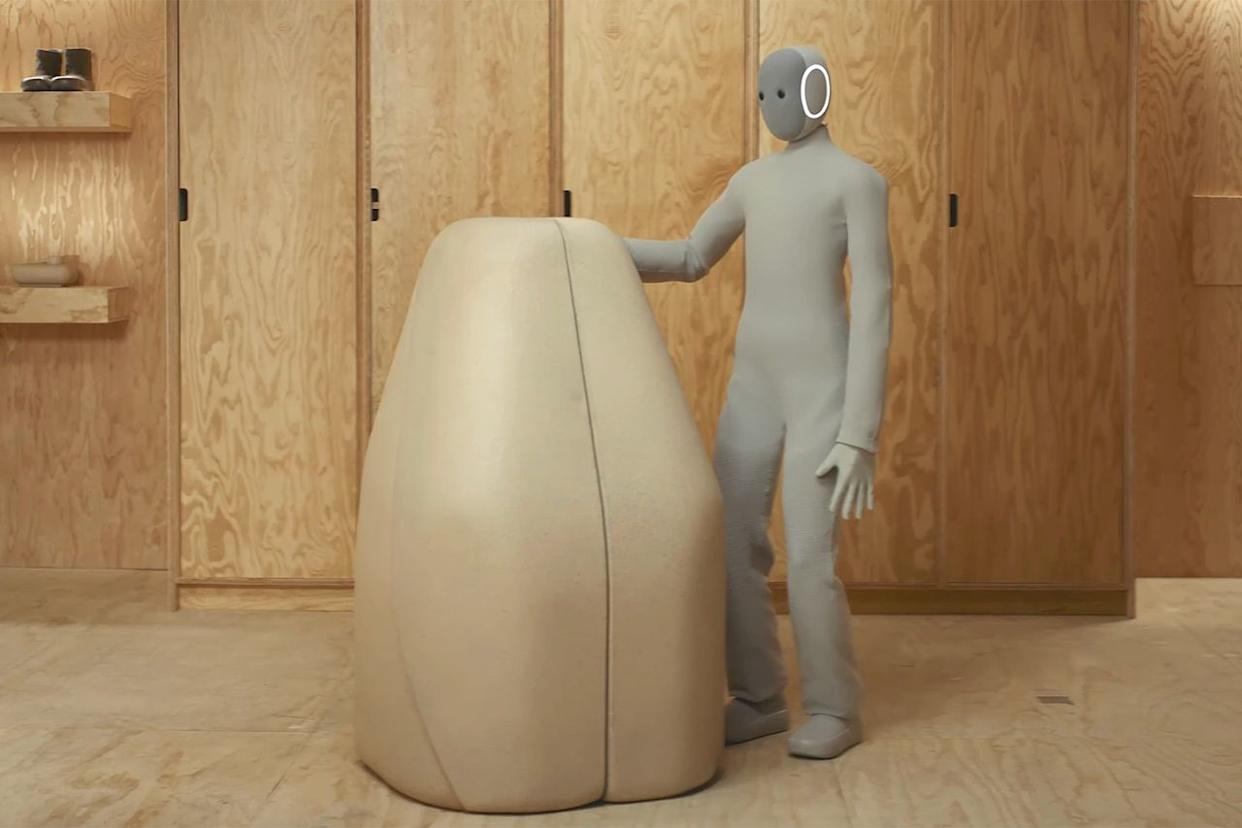 1X NEO humanoid robot standing next to its charging station dock in a home environment