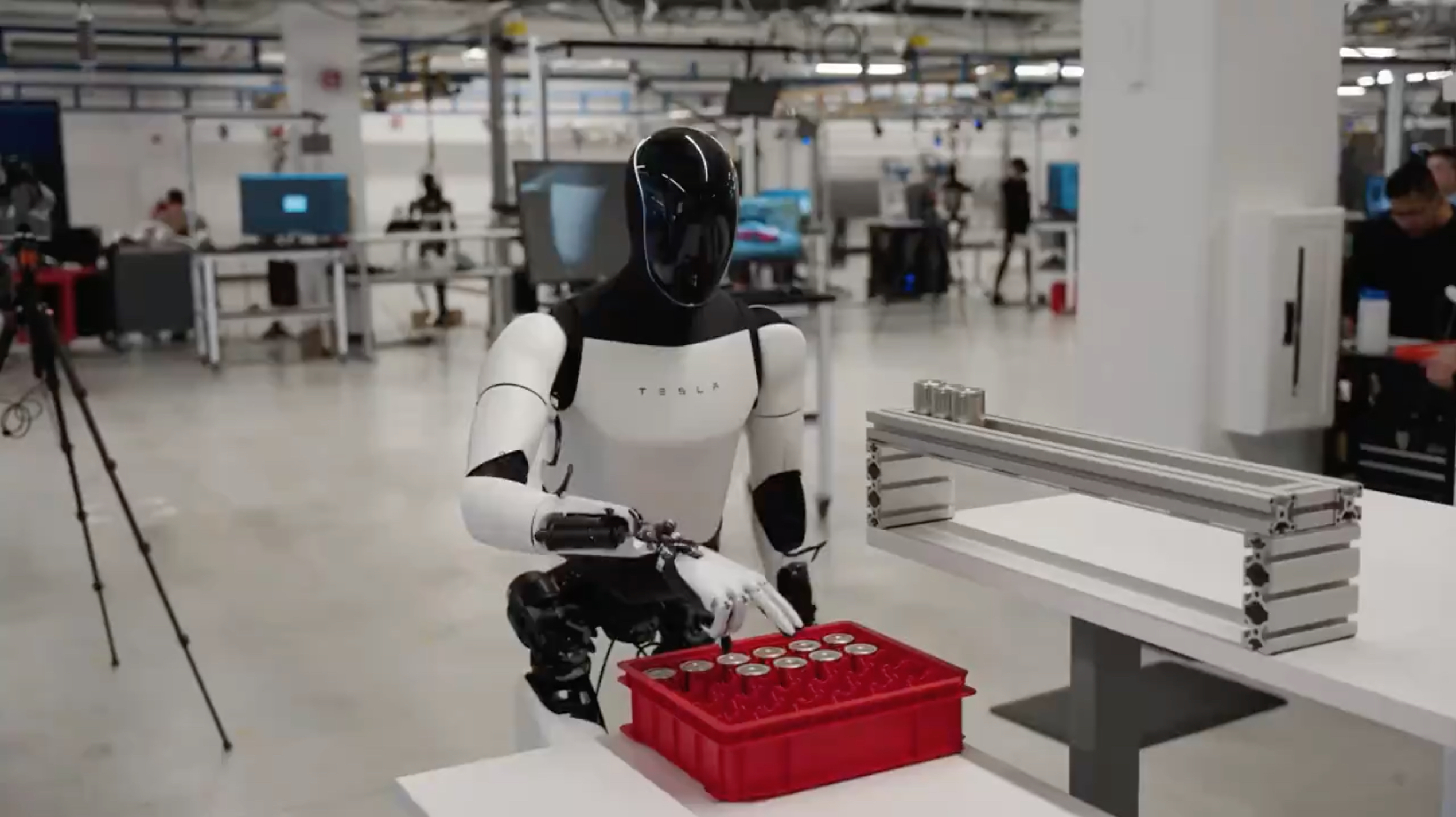 Tesla Optimus humanoid robot sorting 4680 battery cells at Tesla Gigafactory, demonstrating real-world industrial task capability with precise manipulation of small cylindrical components