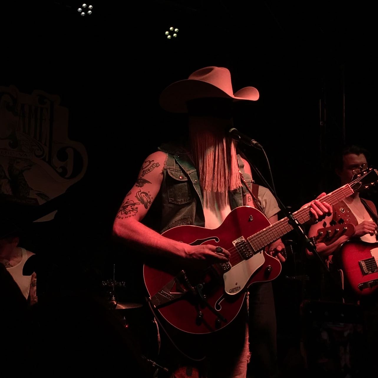 Orville Peck performing with a red guitar at The Camel