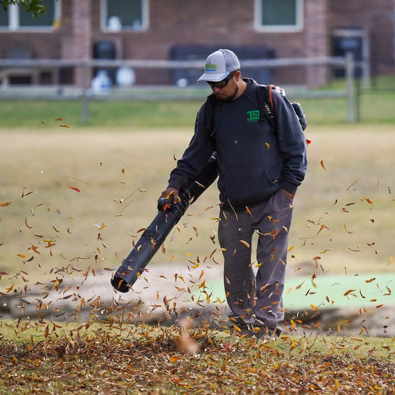 Worker using a leaf blower for lawn maintenance near me in Jenks by TnT Premier Landscape