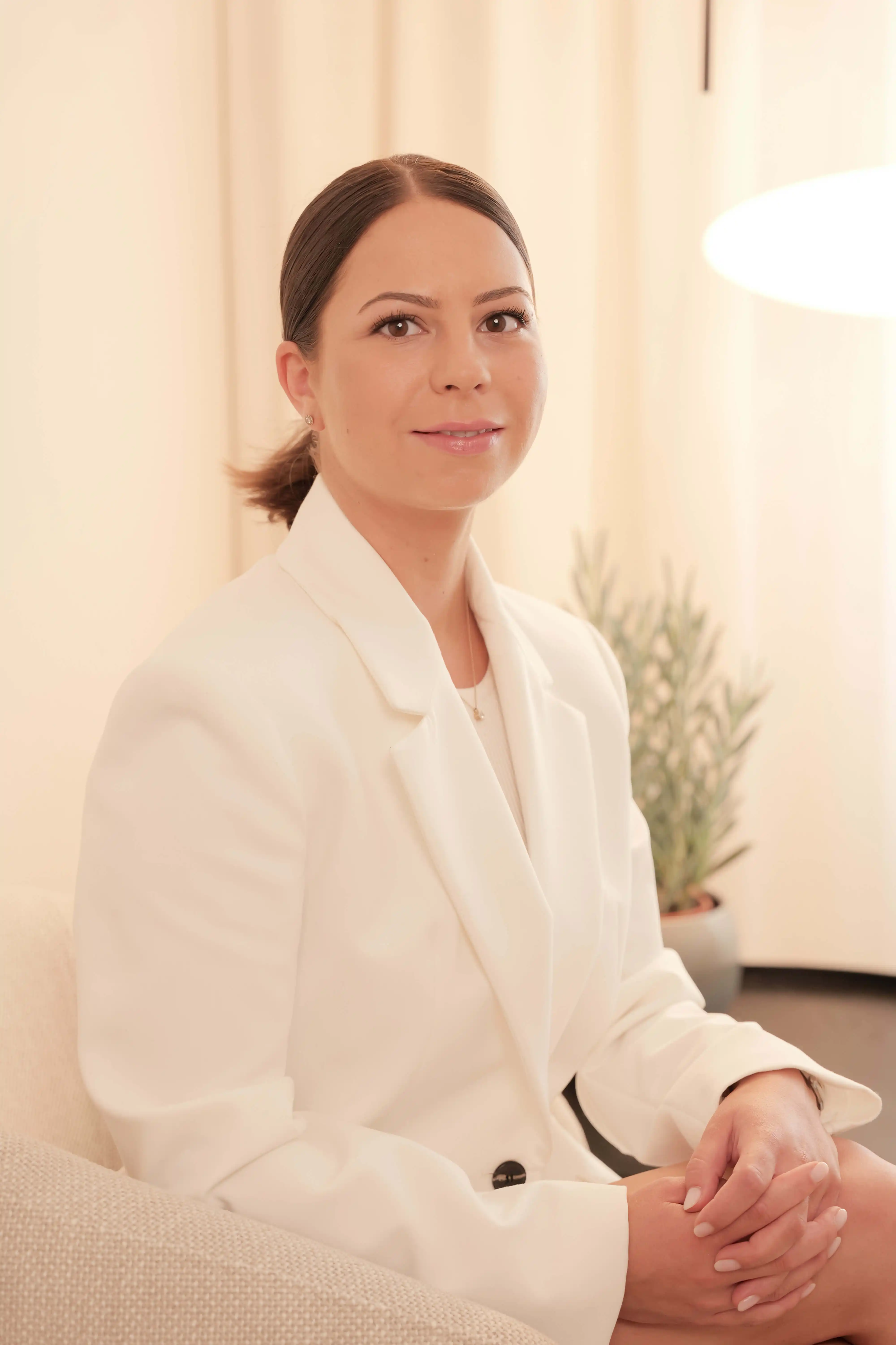 there is a woman sitting on a couch in a white suit